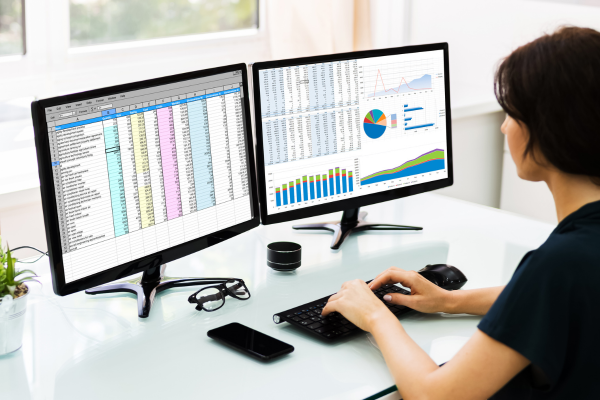 Woman looking at two computer screens.