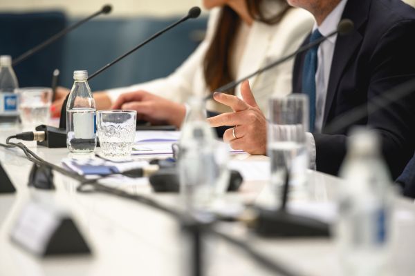 Woman and man at press table with microphones and name cards.